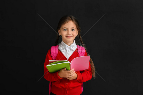 深色背景中带习字簿的小女学生图片