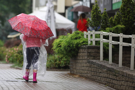 街上雨中打着红伞的小女孩图片