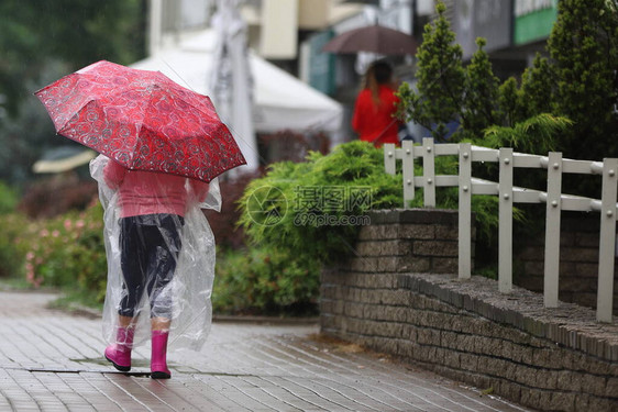 街上雨中打着红伞的小女孩图片