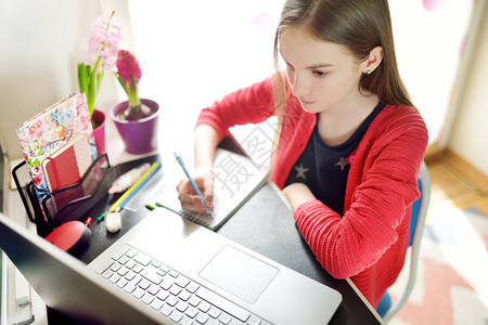 青春期前的女学生在家里用笔记本电脑做作业孩子使用小工具学习孩子们的在线教育和远程学习隔离期间在家上图片