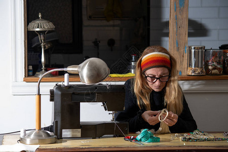 一个金发女人利用隔离时间缝补衣用缝纫机在家里换图片