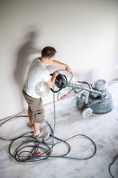 家庭客厅的建筑工人在应用环氧树脂地板之前研磨混凝土表面聚氨酯和环氧树脂地板图片
