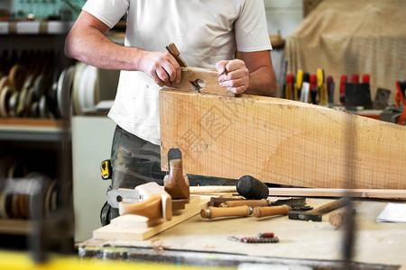木匠在木工车间的前景中用手动刨床打磨或减少表面的木块图片