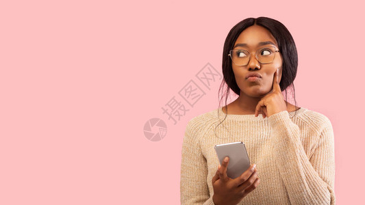 深思熟虑的黑人妇女持有移动电话思考触摸着Chin图片