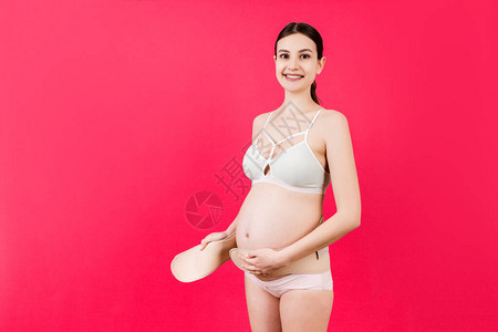身穿彩色内衣的孕妇在粉红色背景上贴绷带图片