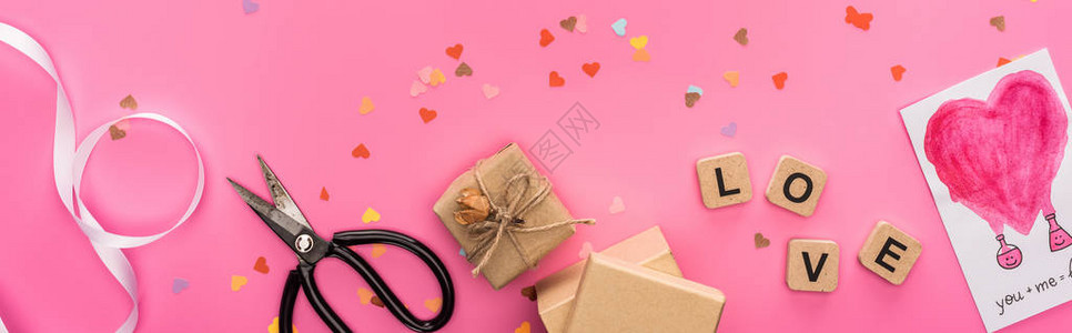 情人节纸屑剪刀礼品盒贺卡和粉红色背景木制立方体上的情书的顶视图片
