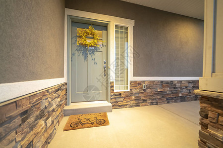 与灰色门黄色花环和侧灯的家前外部视图外墙由混凝土和石砖图片