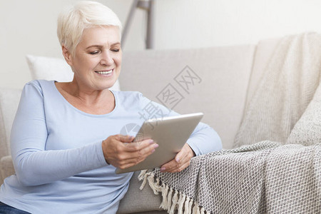 快乐的年老妇女使用数字平板电脑图片