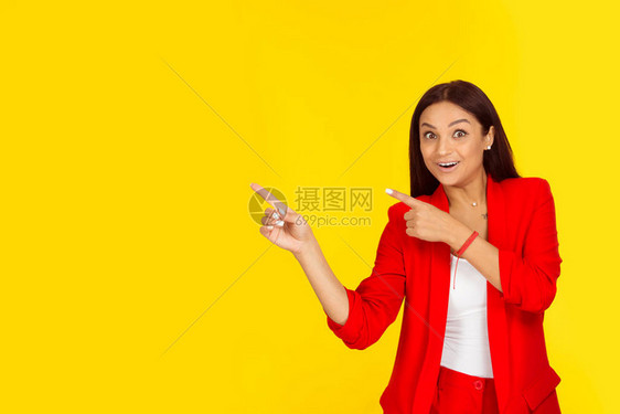 肖像快乐美丽兴奋的女人用食指向孤立在黄色背景上的一侧积极的面部表情绪感觉肢体语言感知图片