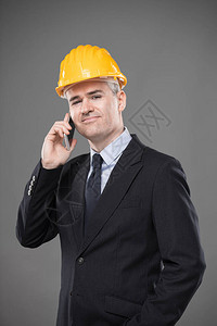 身着智能西装领带和安全帽的友好微笑建筑师或结构工程师站在手机上聊天图片