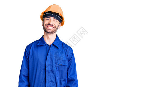 身穿工人制服的西班牙年轻人面带快乐和凉爽的笑图片