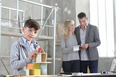 快乐的孩子和他的家人在室内场地玩建筑模型的房子购房和图片