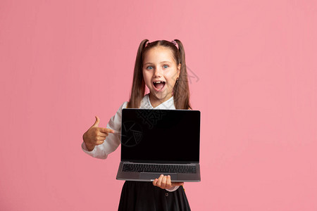 快乐的小女孩在笔记本电脑上用空白屏幕张开嘴孔展示图片