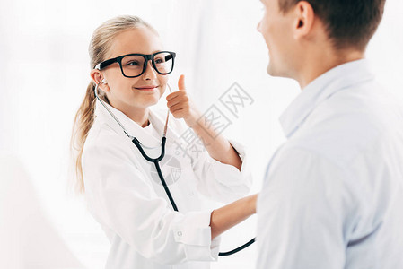 穿着医生服装的孩子用听诊器检查病人图片