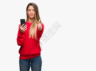 漂亮的年轻女人用智能手机开心地笑着做好的手势图片
