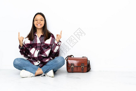 坐在地板上的年轻女学生指着一背景图片