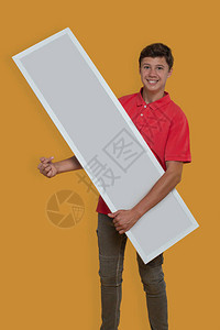 一个微笑的小男孩拿着带有复制空间的白色广告牌并在黄色背景的广告上展示广告背景图片