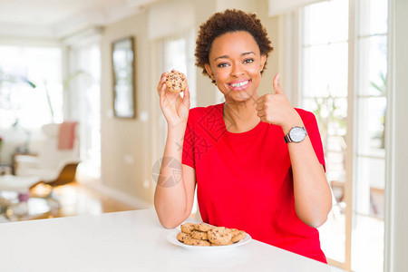 年轻非洲女人吃巧克力薯片饼干快乐的笑做好牌子图片