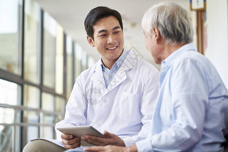 友好微笑的亚洲年轻医生向住院的老年患者交谈和图片