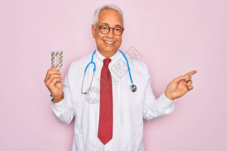 中年高白头发老年灰发医生男子在粉红背景上持有处方药图片