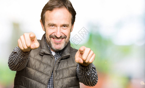 西安冬中年英俊男子身穿冬背心指着你和摄影机用手指着镜头微背景