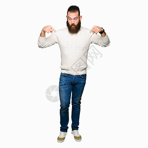 穿着冬季毛衣的年轻时装男子指着手指向下展示广告惊异的图片