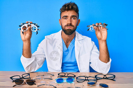 年轻的西班牙裔男子戴着验光眼镜坐在桌旁图片