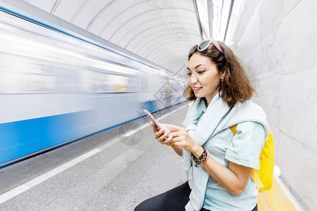 亚洲女人在等火车时在地铁里使用智能手机移动运输应图片