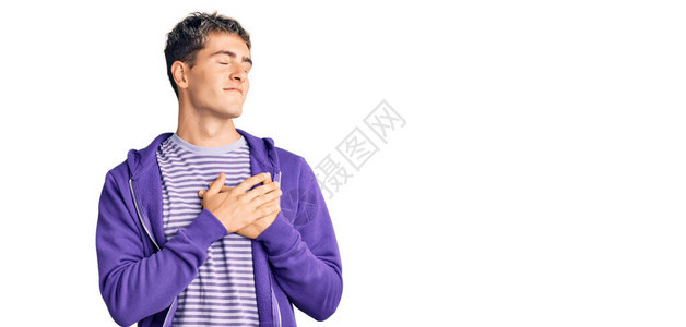 身穿紫色散漫运动衫的英俊男青年在胸前微笑图片