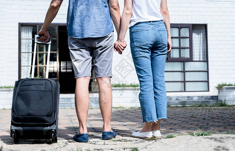 拖着行李搬进新家的夫妇的背影是他们为开始生活和家庭而购买的新家图片