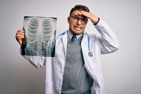 身穿医用外套的年轻医生在孤立的背景下看着胸部扫描X光片图片