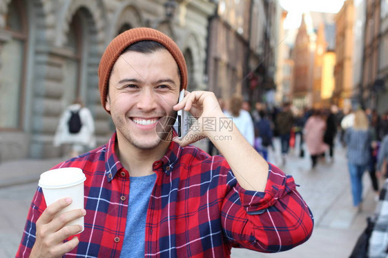英俊年轻男子在街上通过电话交图片