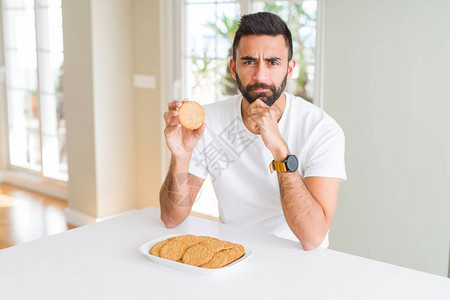 西班牙裔帅哥吃健康全麦饼干严肃的脸思考问题图片