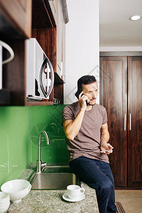 坐在厨房柜台时在电话上说话和点菜的重图片