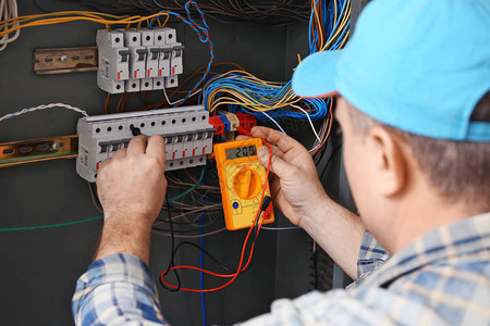 成熟电工在配电盘中测量电压背景图片