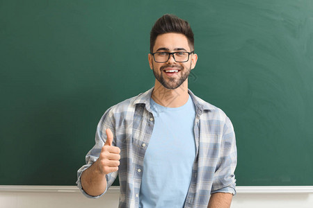 男老师在教室的黑板旁竖起大拇指背景图片