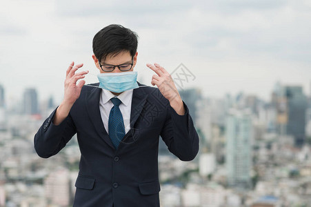 年轻英俊的亚洲商人戴着保护污染和的面具站在城图片