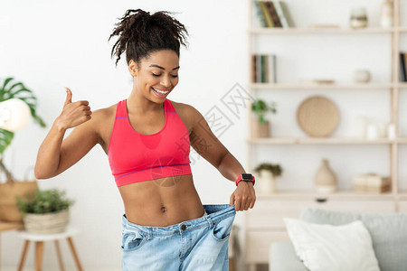 快乐的非洲女士显示成功减肥的结果图片