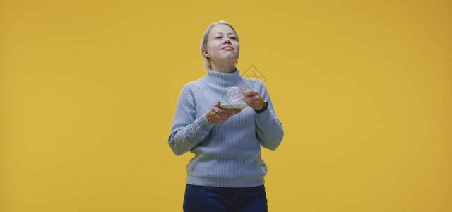 一名年轻女子在黄色背景下喝咖图片