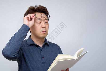 亚裔男试图读懂他书里的东西糟糕的目光图片