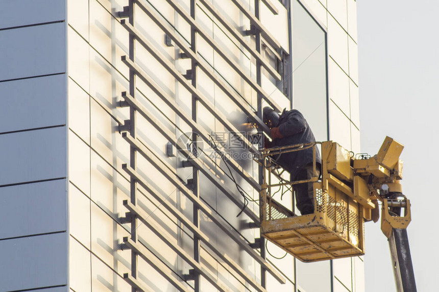 利用电焊接汽车升降电话为搬运工人修理大楼外墙图片