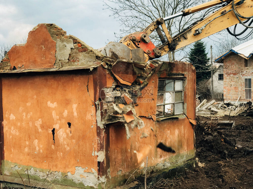 挖掘机摧毁农村土地上的砖房推土机用旧砖块和混凝土从墙上用泥土和垃圾清理土地反铲图片