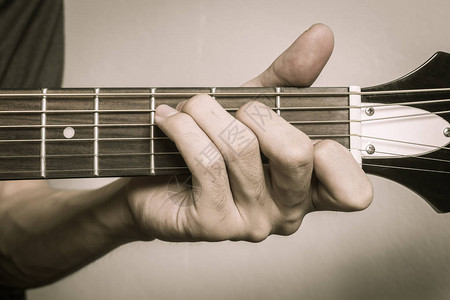 吉他玩家手或音乐手在C大和弦在近视中以软自然光显示图片