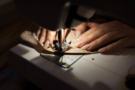那个女人正在用缝纫机缝制缝纫是使用针和线制成的针迹固定或连接物体的工艺缝纫是最古老的图片