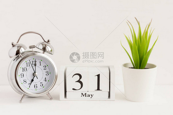 5月31日在闹钟和花旁边的木制日历上春季月份的一天图片