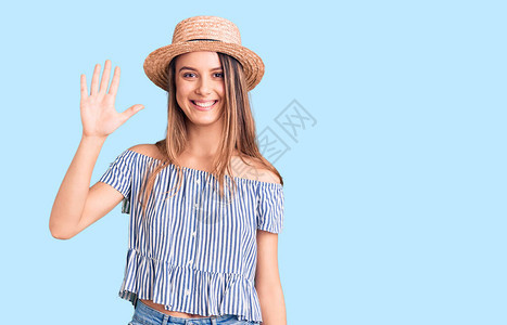 穿着帽子和T恤的年轻漂亮女孩带着五指向上面微笑着自信和快乐图片