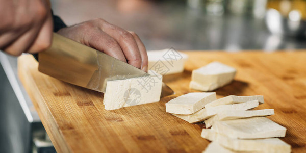 准备素食餐厨师用刀在木板上切豆腐奶酪图片