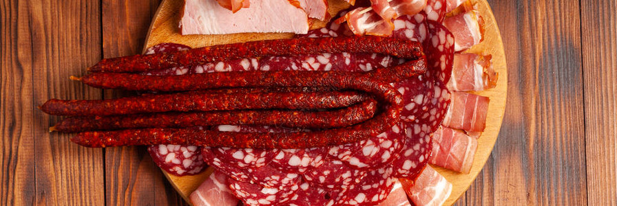 木制砧板上的各种肉类小吃香肠火腿培根熏肉制品库存图片