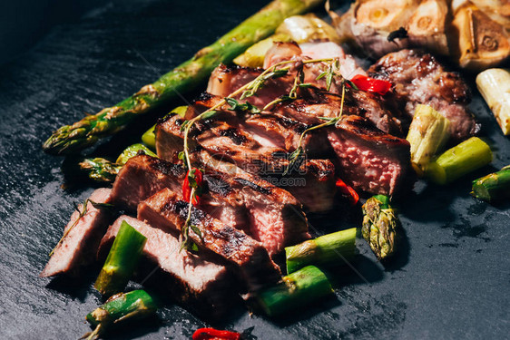 特写烤肉片配芦笋和黑色香料图片