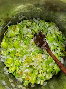 用木勺在锅里放青椒和洋葱图片